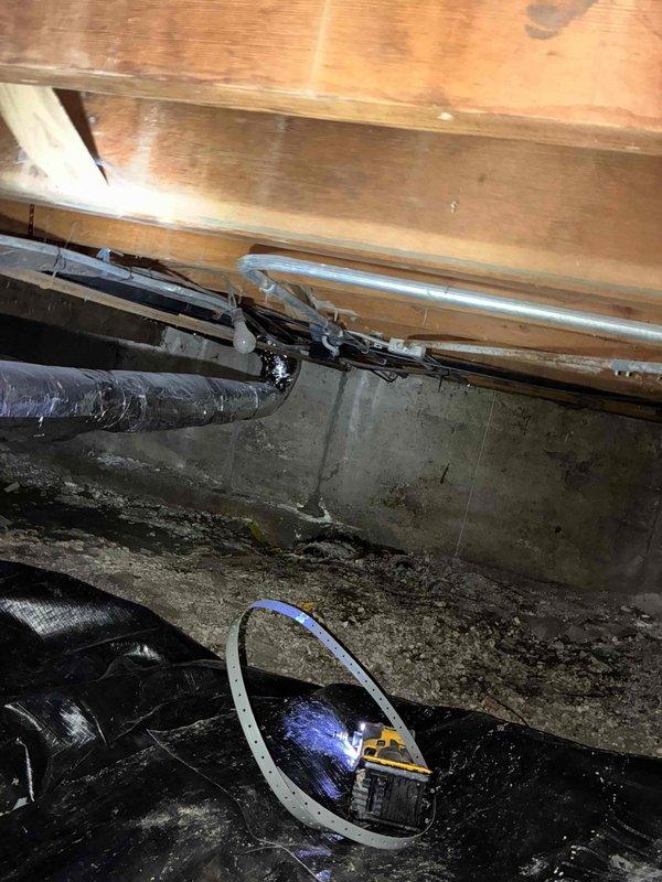 Responded to warranty callback regarding refrigerant line installation in crawl space. Entered wet crawl space and performed thorough inspection of refrigerant lineset routing and support. Found lineset hanging lower than optimal clearance from concrete floor surface, which showed evidence of moisture and biological growth. Secured and re-supported refrigerant lines using additional metal strapping to wooden floor joists above, achieving proper clearance from ground surface. Verified all insulation remained intact on lineset throughout crawl space. Documented conditions with photos and reviewed completed work with customer on site, confirming concerns were addressed to satisfaction.