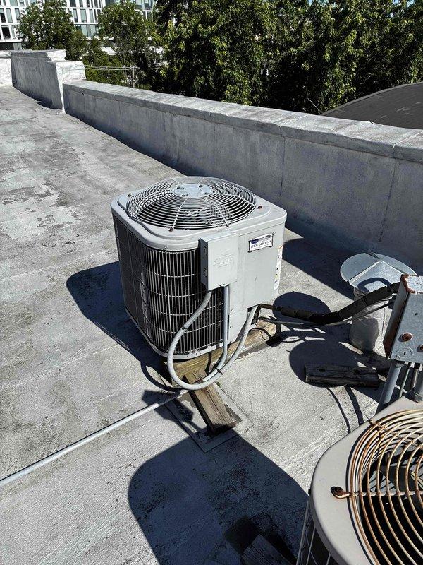 Responded to no cooling complaint on rooftop package unit. Upon arrival, tested supply air temperature at return grille which registered a FAIL reading on digital thermometer, confirming inadequate cooling performance. Inspected outdoor condensing unit on roof, noting system operational status and documented refrigerant line connections and mounting configuration for further diagnostic evaluation.