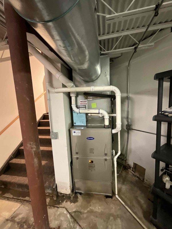 Conducted site assessment for rooftop unit replacement on commercial building. Documented existing weathered RTU showing significant age-related deterioration, rust staining, and surface corrosion on metal exterior panels. Inspected rooftop conditions including metal panel construction and evaluated accessibility for equipment replacement. Also assessed basement mechanical room housing Carrier furnace unit with associated PVC ventilation piping and ductwork to determine scope of potential additional HVAC system work. Provided comprehensive photographic documentation of both rooftop and basement equipment for replacement quote preparation.