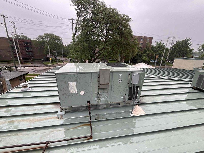 Conducted site assessment for rooftop unit replacement on commercial building. Documented existing weathered RTU showing significant age-related deterioration, rust staining, and surface corrosion on metal exterior panels. Inspected rooftop conditions including metal panel construction and evaluated accessibility for equipment replacement. Also assessed basement mechanical room housing Carrier furnace unit with associated PVC ventilation piping and ductwork to determine scope of potential additional HVAC system work. Provided comprehensive photographic documentation of both rooftop and basement equipment for replacement quote preparation.