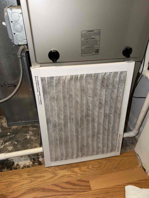 Completed comprehensive AC clean and check maintenance agreement on 18-year-old air conditioning system. Primary focus was condenser coil cleaning due to heavy dust accumulation from gravel alley exposure in shared mechanical room housing multiple units with open walls. Utilized cordless pressure washer to thoroughly clean condenser coil of accumulated debris. Inspected evaporator coil assembly, noting copper refrigerant lines in good condition with normal patina. Replaced air filter showing moderate dust loading. Inspected newer furnace unit, confirmed proper operation. System operational upon completion.