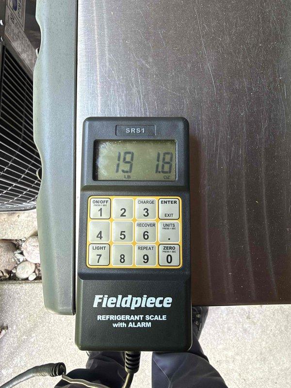 Returned to system to add refrigerant as scheduled. Connected Yellow Jacket Titan 4-valve manifold gauges to measure system pressures and verify refrigerant levels. Used Fieldpiece SRS1 refrigerant scale with alarm to accurately measure and charge system to manufacturer specifications. System pressures restored to proper operating range and unit returned to normal operation.
