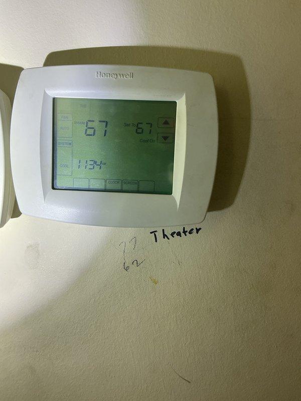 Performed inspection of rooftop unit serving theater space to assess serviceability and determine refrigerant type for potential maintenance agreement enrollment. Accessed RTU on flat membrane roof using telescopic ladder, documented thermostat location and current settings showing 67°F in cooling mode, and photographed equipment specifications including refrigerant data plate information. Confirmed unit is serviceable and provided recommendations for ongoing maintenance program eligibility.