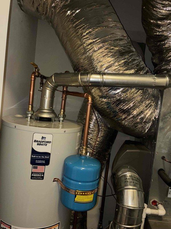 Replaced existing 40-gallon Bradford White tanked water heater in residential mechanical room. Installation included connecting copper supply lines with brass fittings, installing blue expansion tank on the hot water outlet, and reconnecting gas supply line to the unit. All plumbing connections were properly secured and tested for leaks to ensure system integrity and safe operation.