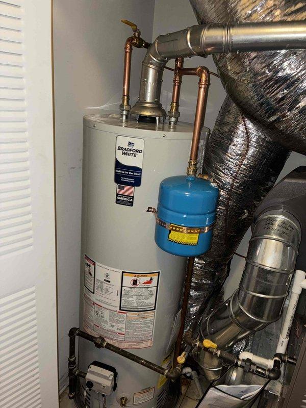 Replaced existing 40-gallon Bradford White tanked water heater in residential mechanical room. Installation included connecting copper supply lines with brass fittings, installing blue expansion tank on the hot water outlet, and reconnecting gas supply line to the unit. All plumbing connections were properly secured and tested for leaks to ensure system integrity and safe operation.
