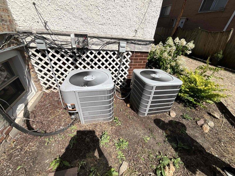 # HVAC System Replacement Estimate

Evaluated two 2012 cylindrical air conditioning condenser units experiencing refrigerant leaks following improper refrigerant addition by another service provider. Both outdoor units showed signs of age and deterioration, positioned on weathered concrete pad in confined outdoor utility area. Indoor furnace system inspection revealed equipment housed in utility closet with visible floor staining and discoloration indicating potential historical leak issues. Provided comprehensive replacement estimate comparing repair costs versus full system replacement options for dual AC configuration with existing furnace infrastructure.
