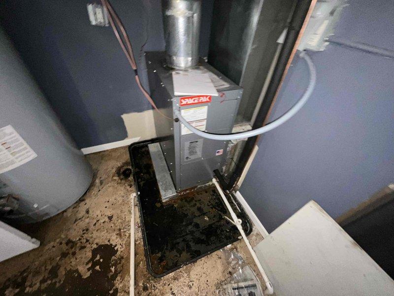 # HVAC System Replacement Estimate

Evaluated two 2012 cylindrical air conditioning condenser units experiencing refrigerant leaks following improper refrigerant addition by another service provider. Both outdoor units showed signs of age and deterioration, positioned on weathered concrete pad in confined outdoor utility area. Indoor furnace system inspection revealed equipment housed in utility closet with visible floor staining and discoloration indicating potential historical leak issues. Provided comprehensive replacement estimate comparing repair costs versus full system replacement options for dual AC configuration with existing furnace infrastructure.