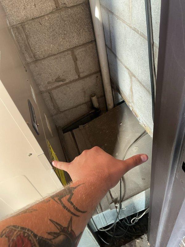 Responded to no cooling complaint on 4-year-old AC system in apartment unit. Upon arrival, encountered severely restricted access to equipment due to extremely narrow mechanical space with limited clearance around air handler. Documented space constraints with measurements and photographs showing concrete block enclosure with minimal working room. Due to physical access limitations preventing standard service procedures, coordinated technician reassignment to complete necessary diagnostics and repairs with personnel better suited for confined space work.