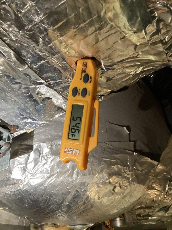 Responded to no cooling complaint on dual-zone upstairs HVAC system over 10 years old. Upon inspection, found significant air leakage around unit ductwork where insulation and duct tape had deteriorated and pulled away from seams. Measured supply air temperature at 97.5°F, confirming inadequate cooling performance. One zone experiencing intermittent cooling while second zone showed minimal cooling capacity. Observed standing water with algae growth and sediment accumulation in condensate drain pan, indicating drainage issues. Documented extensive duct leakage at air handler contributing to reduced airflow and inefficient zone temperature control. Recommended duct sealing and insulation repair to address conditioned air loss, along with condensate pan cleaning and drain line service to prevent water damage and maintain proper system operation.