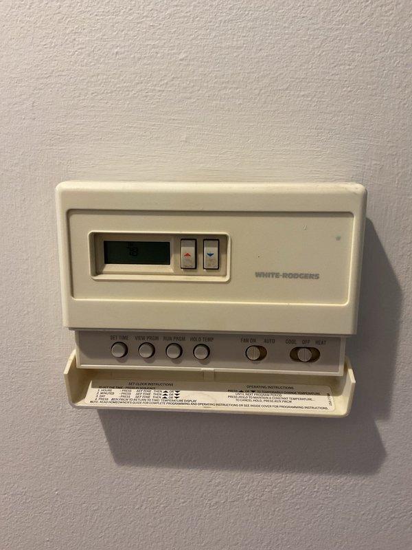 Responded to callback for AC unit not cooling following service performed two weeks prior. Upon arrival, inspected thermostat operation and verified settings on White-Rodgers digital control unit. Proceeded to air handler location and discovered significant rust staining on concrete pad beneath condensate pump assembly, indicating historical water accumulation or drainage issues. Inspected condensate removal system including pump housing, PVC drain line connections, and electrical wiring. System evaluation revealed potential condensate drainage concerns that may have contributed to unit performance issues reported by customer.