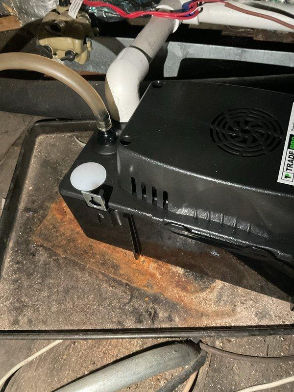 Responded to callback for AC unit not cooling following service performed two weeks prior. Upon arrival, inspected thermostat operation and verified settings on White-Rodgers digital control unit. Proceeded to air handler location and discovered significant rust staining on concrete pad beneath condensate pump assembly, indicating historical water accumulation or drainage issues. Inspected condensate removal system including pump housing, PVC drain line connections, and electrical wiring. System evaluation revealed potential condensate drainage concerns that may have contributed to unit performance issues reported by customer.