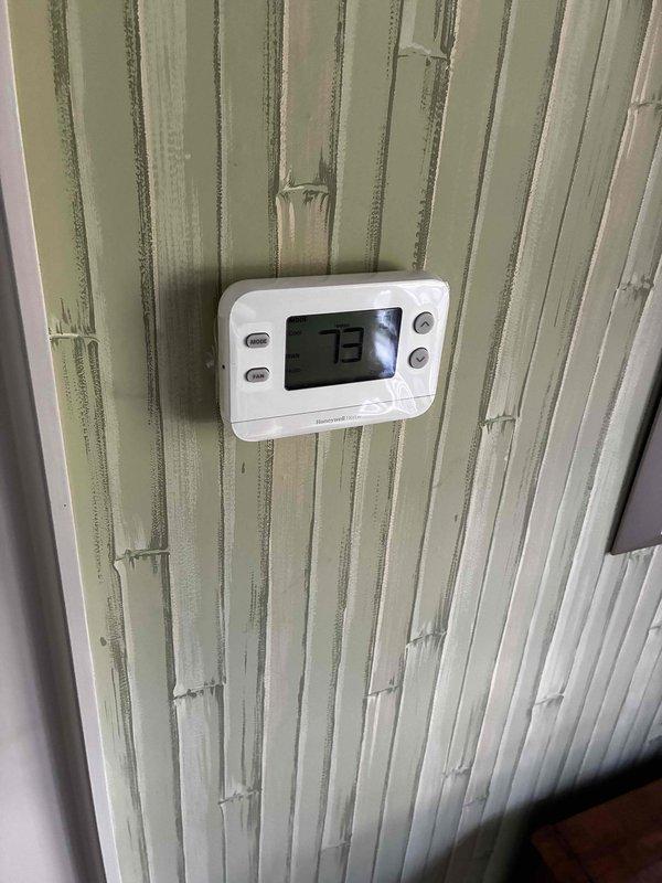 Responded to service call for non-functioning thermostat. Inspected existing Honeywell digital thermostat displaying 73 degrees on wall-mounted beadboard. Accessed HVAC system wiring at equipment location and verified low-voltage control circuit connections including red, white, and blue thermostat wires with proper wire nut terminations. System wiring and connections found secure and operational.