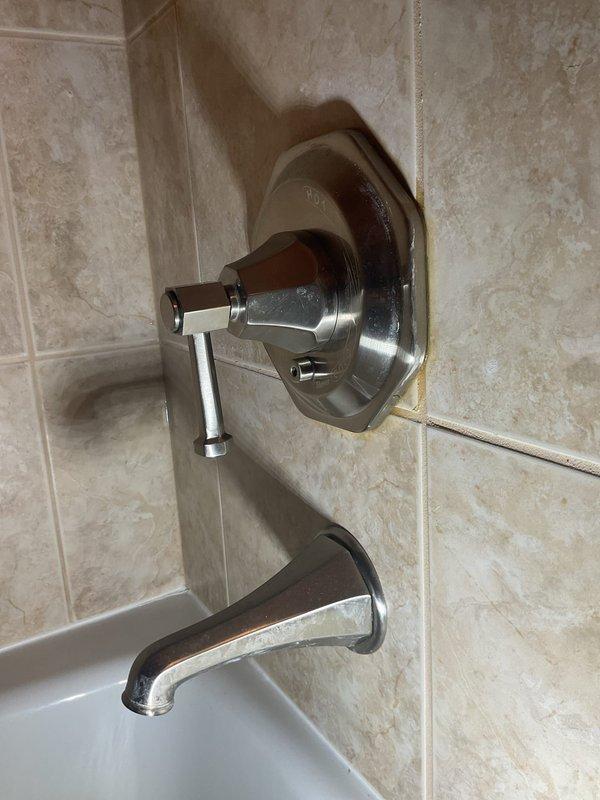 Responded to service call for leaking bathtub fixture. Upon inspection, identified deteriorated valve assembly and corroded escutcheon plate causing water seepage. Removed old tub and shower diverter valve system, replaced with new chrome-finished fixture assembly including circular escutcheon plate, T-handle diverter valve control, and matching curved tub spout. Tested system for proper operation and verified all connections are watertight with no leaks present.