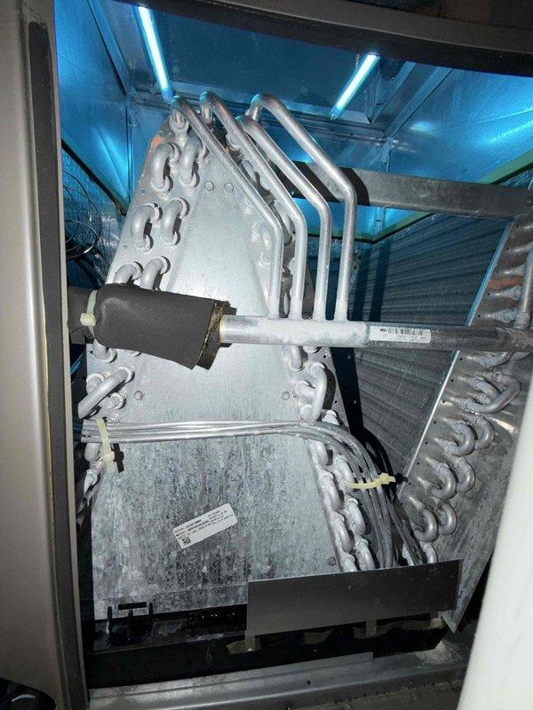 Responded to no cooling complaint and discovered evaporator coil completely frozen over with heavy ice accumulation on heat exchanger and refrigerant lines. Diagnosed frozen coil condition caused by restricted airflow or possible refrigerant issue. System was shut down to allow ice to thaw before further diagnostics could be performed to determine root cause and complete necessary repairs.