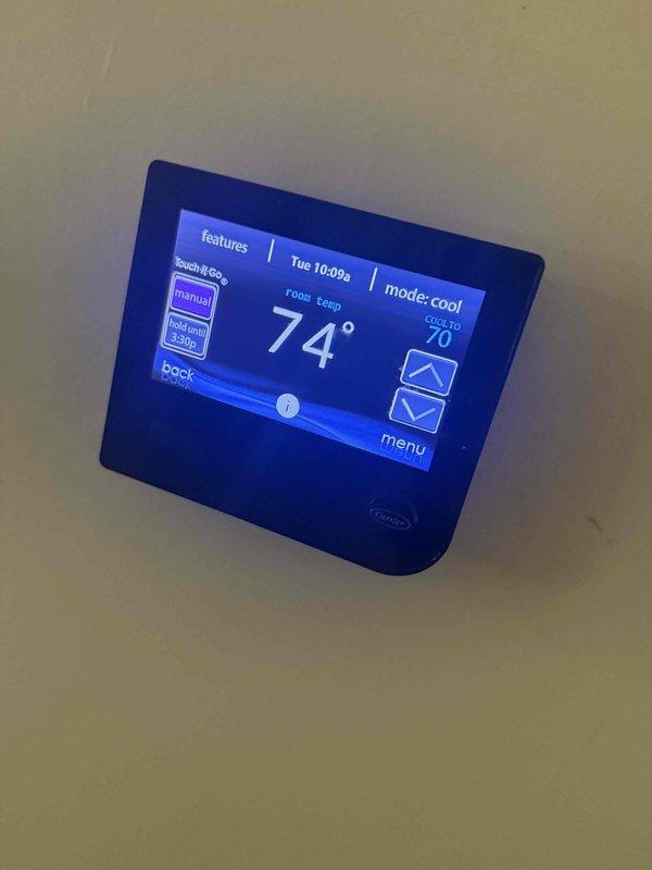 Completed comprehensive air conditioning maintenance agreement inspection on Carrier HVAC system. Performed full checklist including condenser coil inspection for cleanliness and leaks, blower motor and wheel debris check, indoor relative humidity testing, refrigerant level measurement, and cycling of operating controls. Inspected line voltage switch and wiring for safety compliance, verified condensate system drainage, checked all electrical connections for tightness and deterioration, and examined refrigerant lines for visible leaks and insulation condition. System found operating in cooling mode with thermostat set to 70°F and current temperature at 74°F. All components functioning within normal parameters with no immediate concerns identified.