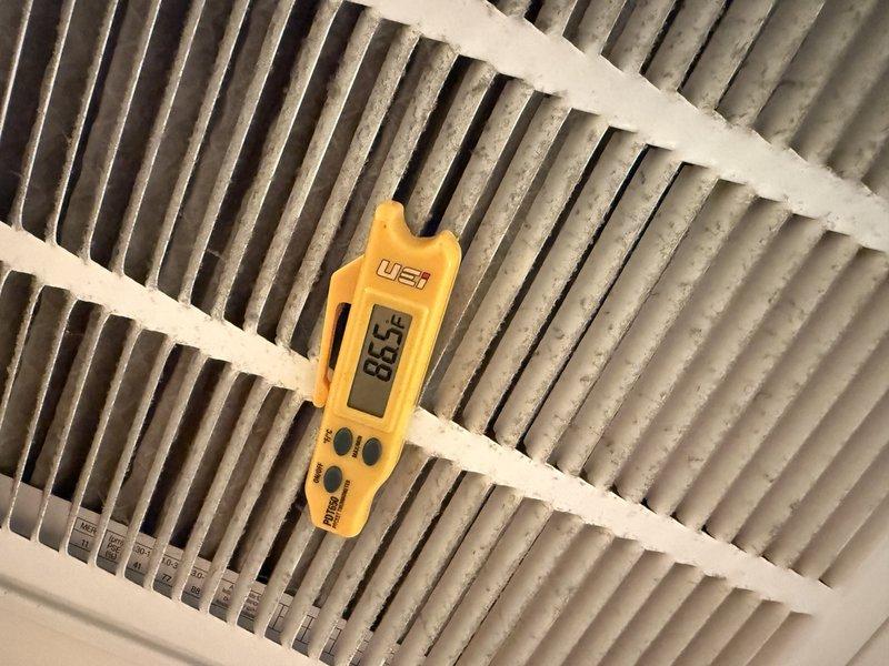 Responded to no cooling complaint on second floor for 10-year-old air conditioning system. Upon arrival, found thermostat displaying 99°F ambient temperature with setpoint at 64°F, indicating system was not achieving desired cooling. Performed diagnostic testing including supply air temperature measurement at register, which recorded 88.5°F—well above acceptable cooling range and confirming inadequate system performance. Noted visible dust accumulation on supply register, suggesting potential airflow restrictions. Accessed outdoor condensing unit without requiring ladder assistance and conducted comprehensive system evaluation to identify root cause of cooling failure.