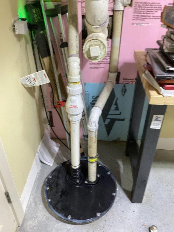 Responded to callback for sewage ejector pump installation experiencing odor issues. Inspected floor seal assembly and pipe penetrations through concrete floor. Verified proper seating of rubber boot seal around dual PVC discharge pipes and confirmed all perimeter bolts were properly torqued to prevent sewer gas escape from pit.