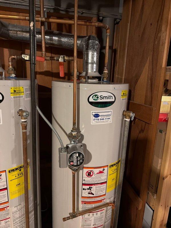 Responded to service call for leaking water heater on AO Smith tanked unit originally installed in 2013. Upon inspection, identified active leak requiring attention and documented existing plumbing configuration including copper supply lines, gas connections with braided flex lines, and metal flue venting system. Photographed installation showing multiple water heater setup with proper venting through galvanized ductwork and assessed overall system condition for repair recommendations.