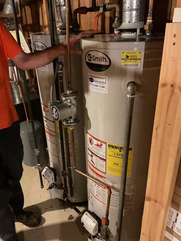 Removed and replaced one 50-gallon water heater from a twinned set installation in basement utility area. Re-piped the plumbing system to accommodate a single water heater configuration, eliminating the dual setup. Reconnected the recirculation line to the new water heater to maintain hot water circulation throughout the system. Capped off the unused exhaust vent and gas line from the removed unit to ensure safe disconnection. Installed new AO Smith 50-gallon residential water heater with proper hot and cold water connections using copper piping. Connected expansion tank above the unit and installed shut-off valves with color-coded handles for easy identification. Verified all pipe connections for proper seal and tested system operation. Cleared obstructions to working area and ensured code-compliant installation.