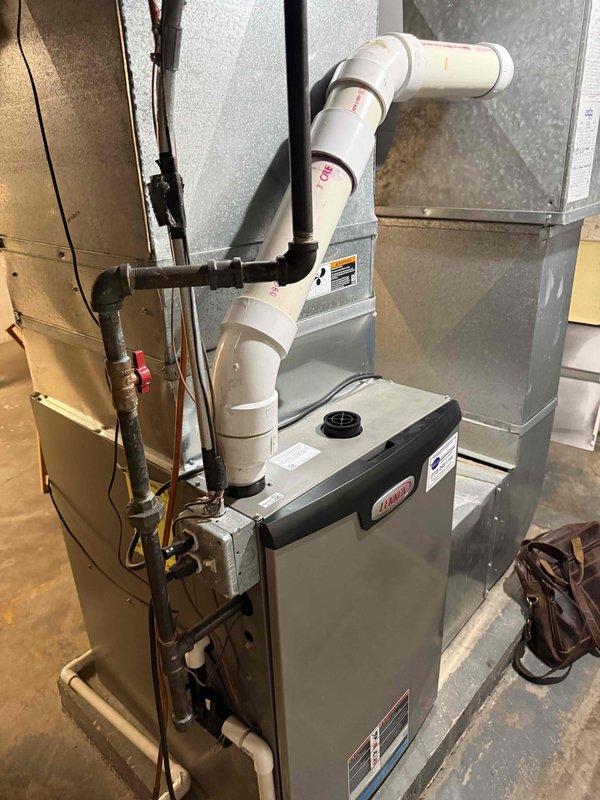Conducted comprehensive assessment of existing HVAC system for full replacement estimate with primary focus on air conditioning components. Evaluated current furnace/air handler unit, ductwork configuration, and associated mechanical systems including humidifier, ventilation piping, and refrigerant lines. Documented system layout showing gray metal air handler with PVC exhaust venting, copper refrigerant piping, flexible and rigid ductwork connections, and electrical service. Photographed equipment specifications, manufacturer labels, and current installation configuration to provide accurate sizing and replacement recommendations for complete system upgrade.