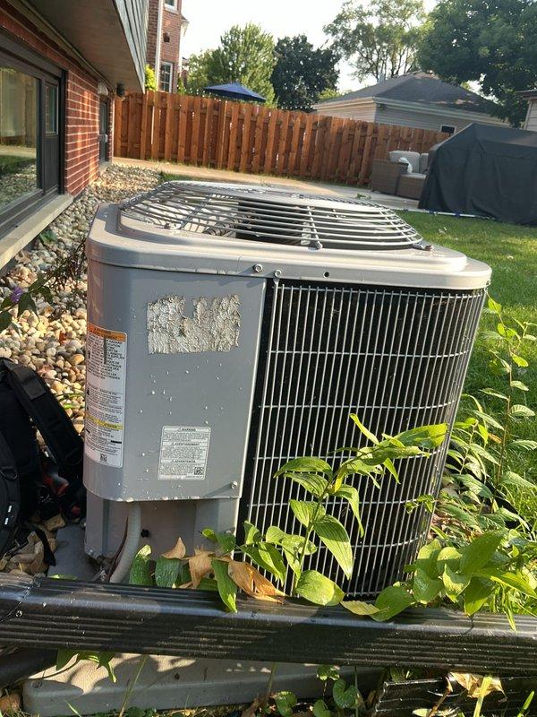 Completed routine maintenance on residential air conditioning system. Inspected outdoor condenser unit, noting vegetation accumulation around base and white residue on exterior panels; cleared debris and verified proper airflow through coil fins. Measured system temperatures at indoor air handler, confirming proper operating temperatures at 83.8°F. Unit operating within normal parameters with no mechanical issues identified.
