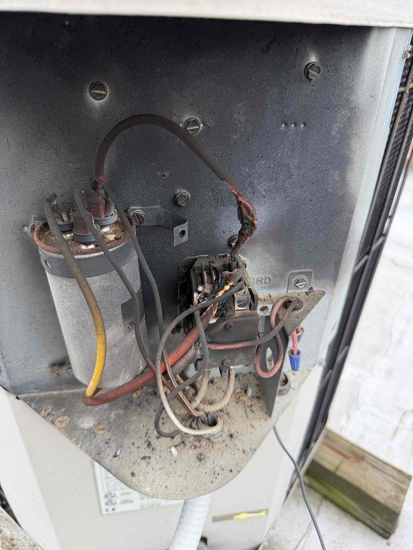 Responded to no cooling complaint on rooftop unit accessed via 15-foot telescopic ladder. Upon inspection, found unit blowing hot air with visible signs of aging electrical components including corroded wire terminals and discolored connections at the contactor assembly. Observed accumulated dirt and debris in electrical compartment along with weathered capacitor and wiring showing service wear. Measured clearances between mechanical components and ductwork to assess system configuration and accessibility for repairs.
