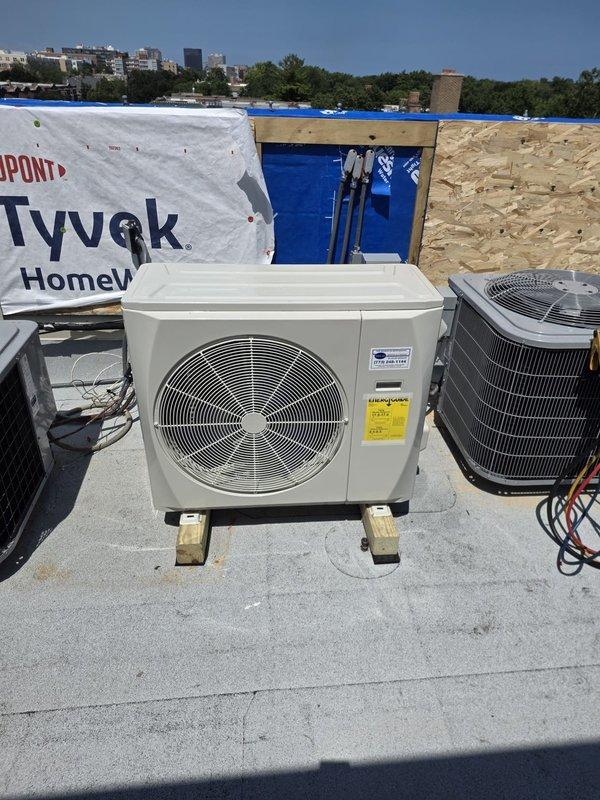Completed return visit to install outdoor air conditioning condenser unit on commercial flat roof. Unit was positioned on wooden blocking for proper elevation and drainage, with refrigerant lines connected and insulated. Installation performed on rooftop alongside existing HVAC equipment in active construction environment, with all electrical connections completed and unit operational upon departure.