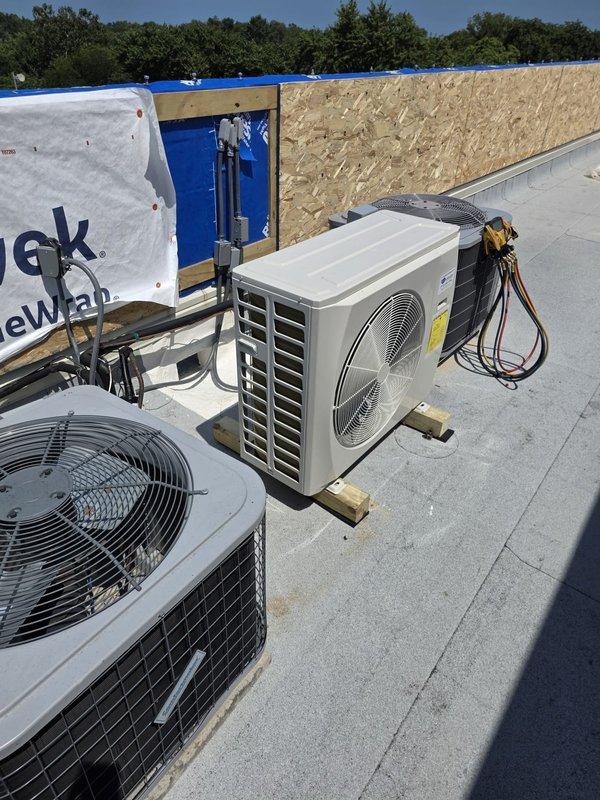 Completed return visit to install outdoor air conditioning condenser unit on commercial flat roof. Unit was positioned on wooden blocking for proper elevation and drainage, with refrigerant lines connected and insulated. Installation performed on rooftop alongside existing HVAC equipment in active construction environment, with all electrical connections completed and unit operational upon departure.