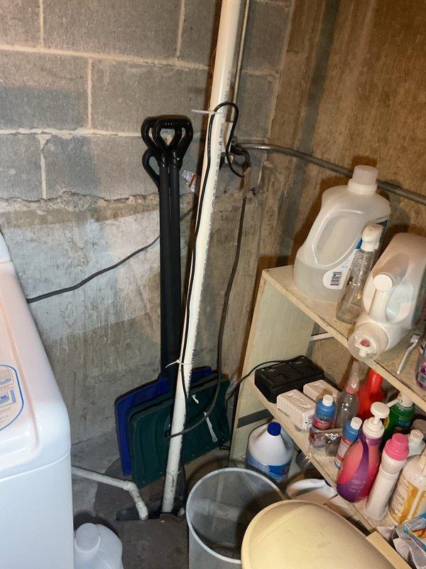 Completed comprehensive plumbing inspection of residential property. Evaluated utility sink installation in basement area, documenting aging concrete basin with significant mineral staining and copper supply lines with shutoff valves showing normal wear. Inspected drainage system, water filtration components, and vertical PVC waste stack with proper mounting brackets. All plumbing systems photographed and assessed for current condition and functionality.