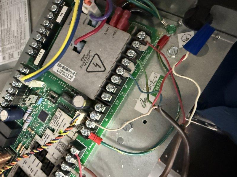 Returned to property to complete warranty work on HVAC system by connecting low voltage wire that was left disconnected on previous visit. Located electrical panel serving dual-zone HVAC system with Lenox upstairs AC condenser and Bosch downstairs AC condenser circuits clearly labeled. Accessed control board assembly and verified proper wire termination at terminal blocks. Connected low voltage control wire to appropriate terminal on circuit board, ensuring secure connection at screw terminal. Verified all wire connections were properly seated and tightened at both the control board and central relay component. Tested system operation to confirm proper communication between thermostat and equipment. System now operating as designed with all control wiring properly connected and functional.