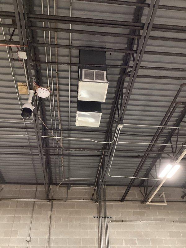 Responded to no cooling call on rooftop unit. Upon arrival, accessed facility using provided lockbox and located RTU above commercial space. Identified active refrigerant leak requiring immediate attention. Placed multiple collection containers on floor beneath unit to capture leaking refrigerant and prevent environmental contamination. Documented leak location and severity with photographs showing RTU mounted to ceiling structure with visible piping infrastructure. Unit requires refrigerant recovery, leak repair, and system recharge to restore cooling operation.