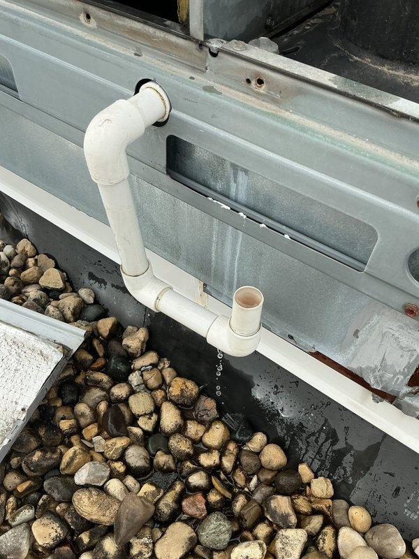 Responded to no-cooling complaint on rooftop unit. Upon arrival, performed diagnostic assessment and discovered severely contaminated condenser coil with heavy dirt and debris accumulation restricting airflow. The coil fins showed extensive buildup that would significantly impact heat transfer efficiency and system performance. Observed condensate drainage system with PVC piping discharging properly to stone drainage bed at equipment base. Documented equipment condition with photos showing the extent of coil contamination and drainage configuration. Recommended thorough coil cleaning to restore proper airflow and cooling capacity.