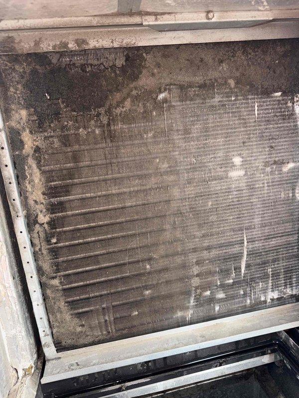 Responded to no-cooling complaint on rooftop unit. Upon arrival, performed diagnostic assessment and discovered severely contaminated condenser coil with heavy dirt and debris accumulation restricting airflow. The coil fins showed extensive buildup that would significantly impact heat transfer efficiency and system performance. Observed condensate drainage system with PVC piping discharging properly to stone drainage bed at equipment base. Documented equipment condition with photos showing the extent of coil contamination and drainage configuration. Recommended thorough coil cleaning to restore proper airflow and cooling capacity.