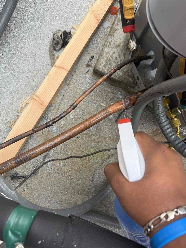 Returned to system to add R-410A refrigerant with sealant, charging up to 3 pounds to address refrigerant loss. Connected manifold gauges to service ports on weathered copper refrigerant lines and performed leak detection procedures. Added leak sealant to system followed by refrigerant charge to restore proper operating pressures and system capacity.