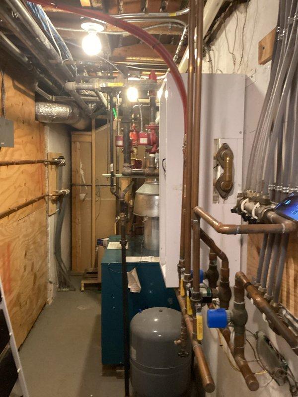 # Plumbing Inspection - Pipe Leak Investigation Near Boiler

Conducted comprehensive plumbing inspection with primary focus on reported pipe leak in vicinity of boiler system. Inspection revealed the leak originated from piping independent of the boiler unit itself, located in the mechanical room area.

## Work Performed

Performed thorough examination of all accessible plumbing systems throughout the property. Inspected basement mechanical room housing water heater, boiler unit, and associated piping infrastructure. Evaluated condition of copper supply lines, PVC drainage systems, and sump pump installation.

Identified leak source at pipe connection near but not integrated with the teal-colored boiler unit. Verified the compromised pipe was part of the general plumbing system rather than boiler-specific components. Assessed surrounding copper piping, insulated lines, and multiple valve assemblies for additional concerns.

Examined sump pump basin with multiple white PVC discharge pip