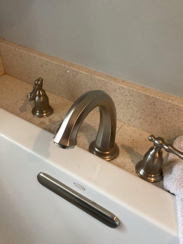 Responded to service call for master bathroom sink with inoperative shut-off valves preventing localized water control. Inspected widespread faucet installation with brushed nickel finish and identified faulty supply line valves requiring customer to use main water shut-off for the entire residence. Documented existing three-piece faucet configuration with separate handles and curved spout mounted on granite countertop. Assessed valve accessibility and photographed installation for repair recommendations.