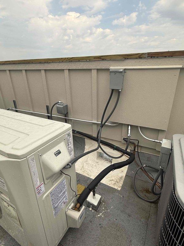 Returned to site to relocate rooftop air conditioning condenser unit approximately 6 inches to the left to provide proper clearance from gas line and water valve. Repositioned electrical disconnect box to wall behind unit for improved accessibility and code compliance. Unit now properly positioned on wooden support blocks with adequate clearance from all utilities and service access maintained.