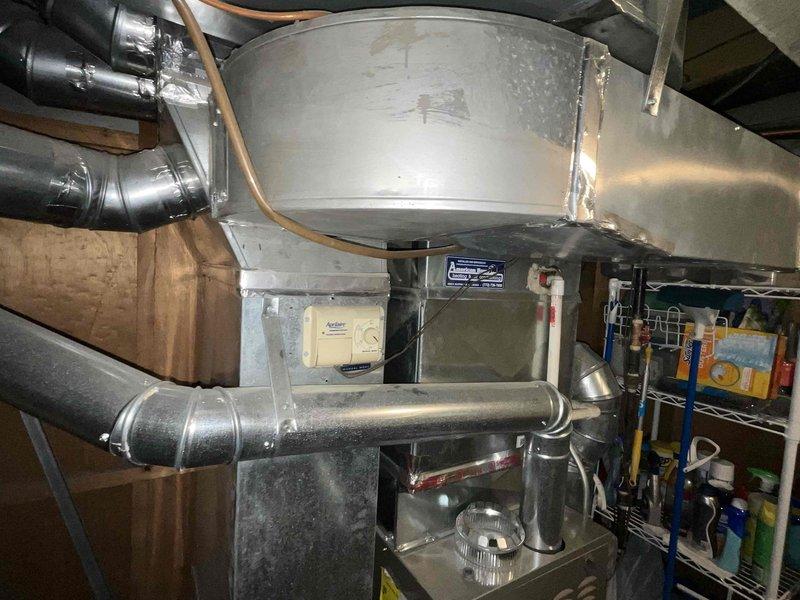 Conducted comprehensive evaluation of 24-year-old Carrier R22 air conditioning system with intermittently failing condenser fan motor. Assessed outdoor condenser unit housed in wooden lattice enclosure and inspected indoor ductwork and plenum assembly in basement mechanical space. Provided detailed replacement estimate for complete AC system upgrade due to obsolete R22 refrigerant phase-out and deteriorating condenser fan motor requiring full system replacement rather than repair of aging equipment.