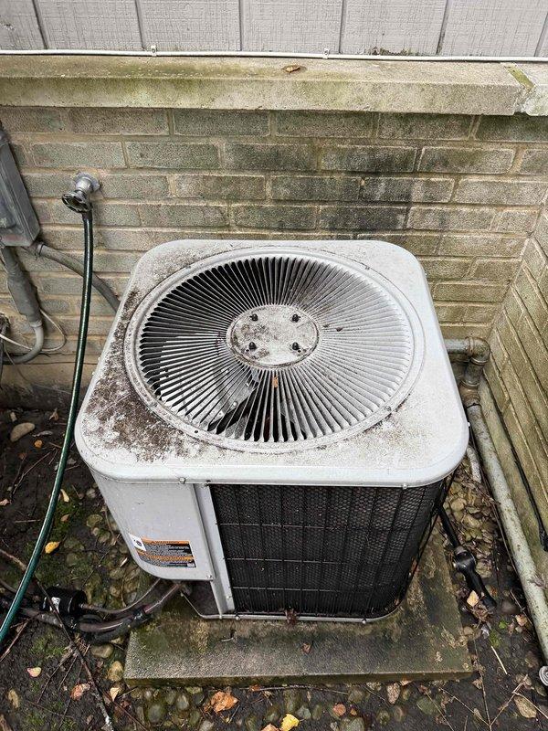 Performed preventative maintenance agreement service on two outdoor condensing units. Both units showed signs of weathering with dirt accumulation and exterior discoloration. Inspected fan assemblies, refrigerant line sets with insulation, and electrical connections. Documented equipment condition with moss/algae growth present on surrounding brick foundation and evidence of moisture-related staining requiring attention for optimal airflow and performance.