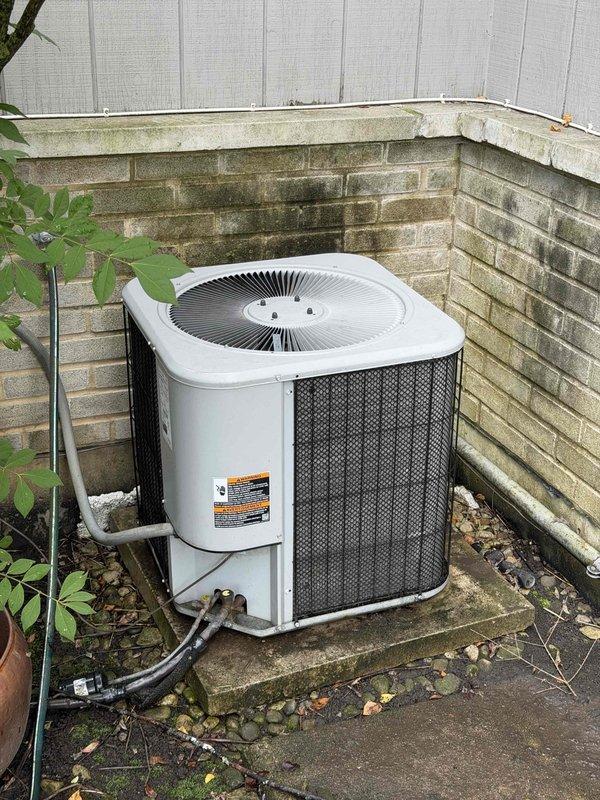 Performed preventative maintenance agreement service on two outdoor condensing units. Both units showed signs of weathering with dirt accumulation and exterior discoloration. Inspected fan assemblies, refrigerant line sets with insulation, and electrical connections. Documented equipment condition with moss/algae growth present on surrounding brick foundation and evidence of moisture-related staining requiring attention for optimal airflow and performance.