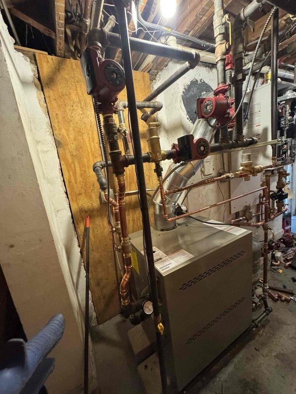 Completed full replacement of residential heating system including installation of new boiler and tankless water heater over a two-and-a-half-day period. Removed existing equipment and installed tan metal boiler unit with copper piping, red circulator pumps, pressure gauges, and proper black iron gas piping with brass valves and fittings. Mounted white wall-hung tankless unit with copper supply lines, installed gray expansion tank, and integrated PEX distribution manifold system for hydronic heating zones. All equipment secured to code with proper venting, verified system pressurization, tested all safety controls, and confirmed operational performance of both heating and domestic hot water systems.