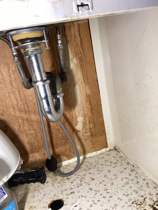 Responded to kitchen sink drainage issue with slow water flow. Accessed plumbing system through under-sink cabinet and inspected P-trap assembly, drain connections, and supply lines. Cleared obstruction from drain line, restoring proper water flow and drainage function. Verified all connections secure with no active leaks present. Documented existing sink staining and cabinet water marks from previous moisture exposure, though no current water damage observed. System tested and confirmed operational upon completion.