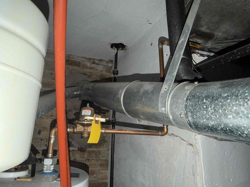 Responded to no cooling call and investigated reported leak from kitchen duct. Upon inspection, found moisture issue in mechanical room affecting ductwork, with drywall already opened by previous plumber. Documented existing plumbing and HVAC infrastructure, including water heater, copper piping with brass fittings, and horizontal duct runs. Measured duct components and assessed system layout to determine source of leak and provide estimate for circulating pump replacement as requested by customer.