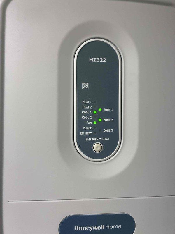 Return visit to system after allowing evaporator coil to thaw from previous frozen condition. Inspected Honeywell zoning control panel showing zones 1 and 2 active, verified thermostat wiring connections at control board including common, heat, cool, and fan circuits. System ready for further diagnostics once coil completely thawed.