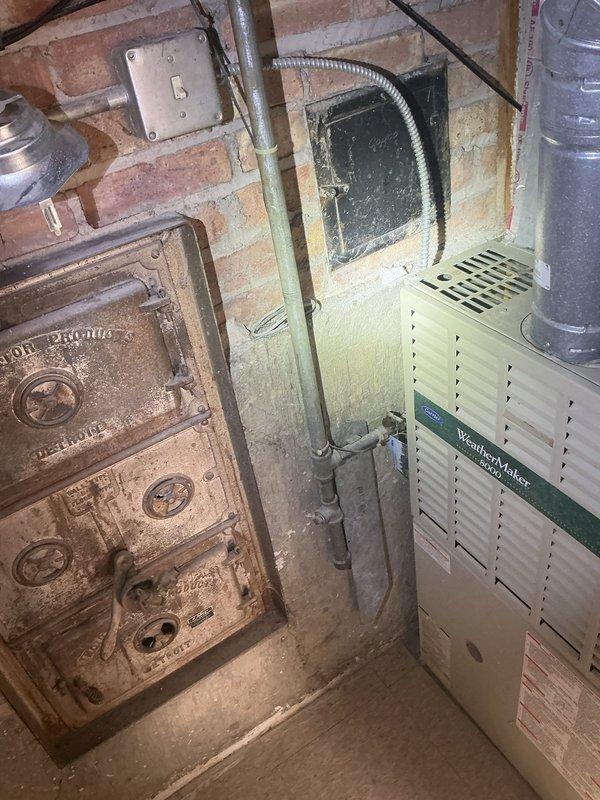 Responded to service call for iced-up evaporator coil on WeatherMaker HVAC system. Upon inspection, confirmed ice buildup on coil and performed defrost procedure. Diagnosed root cause of icing condition and restored system to proper operation. Customer expressed interest in preventative maintenance program enrollment. Documented equipment condition with photographs showing both legacy cast iron boiler and current WeatherMaker furnace installation in basement mechanical room.