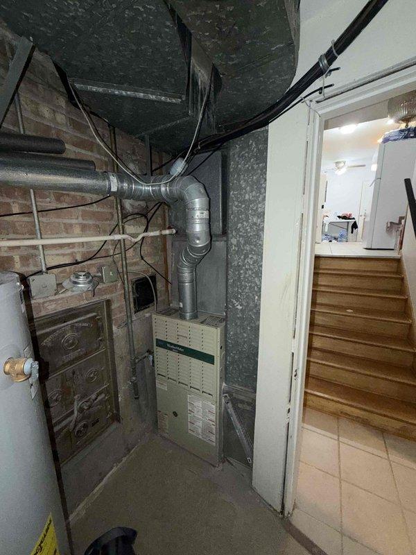 Provided comprehensive estimate for complete HVAC system replacement including both air conditioning and furnace units, both approximately 30+ years old and at end of service life. Assessed existing basement mechanical room installation with aging brown furnace and outdoor condenser unit positioned in side passage between buildings. Documented current system configuration including ductwork, electrical connections, and condensate drainage for replacement specifications.