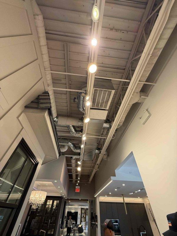 Conducted comprehensive site survey of commercial facility to document all HVAC equipment and components. Identified and photographed all units, recorded model and serial numbers, documented filter sizes, and cataloged thermostat locations and types throughout the space. Survey included exposed ductwork system in industrial-style ceiling area and digital thermostat set at 72 degrees with programmable features.