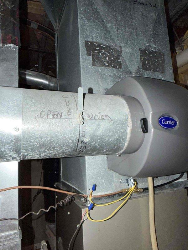 Responded to multiple system issues including tankless water heater error code 600061-01 (abnormal dual venturi) with intermittent hot water loss, and insufficient cooling on third and fourth floor zones. Inspected HVAC system components including Carrier humidifier installation on main ductwork and blower motor assembly. Removed and examined blower motor housing showing significant dust accumulation on squirrel cage fan and motor components. Documented system conditions with photographs for service records. Addressed ventilation concerns and assessed airflow distribution throughout multi-floor system to diagnose temperature control issues in upper zones.