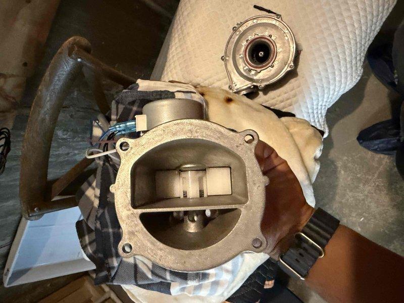 Responded to multiple system issues including tankless water heater error code 600061-01 (abnormal dual venturi) with intermittent hot water loss, and insufficient cooling on third and fourth floor zones. Inspected HVAC system components including Carrier humidifier installation on main ductwork and blower motor assembly. Removed and examined blower motor housing showing significant dust accumulation on squirrel cage fan and motor components. Documented system conditions with photographs for service records. Addressed ventilation concerns and assessed airflow distribution throughout multi-floor system to diagnose temperature control issues in upper zones.
