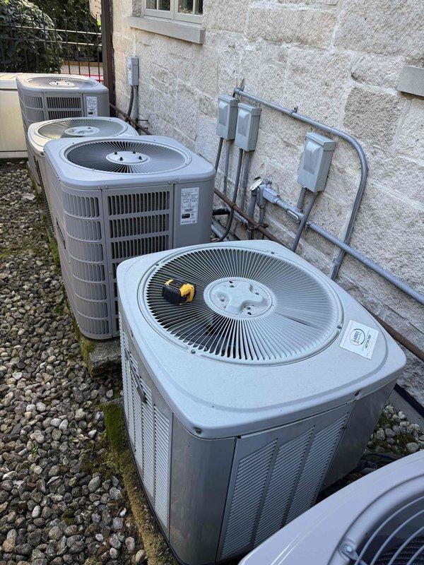 Provided comprehensive estimate for complete replacement of two full HVAC systems serving multi-zone residential property. Existing equipment has exceeded 15-year service life and requires full system changeout. Site assessment documented current configuration of four outdoor condenser units positioned along exterior wall with gravel pad installation, existing electrical disconnects, and refrigerant line routing between mechanical units showing signs of age and weathering.